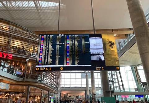 Forsidebilde til innlegget som viser en stor skjerm på Oslo Lufthavn med oversikt over flyavganger