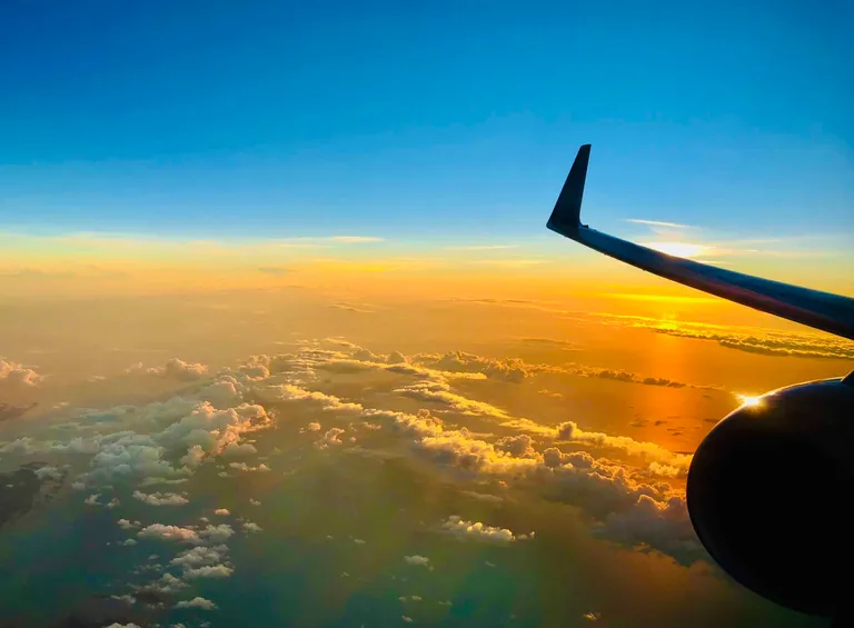 Forsidebilde til innlegget som viser utsikten fra et flyvindu i solnedgang.