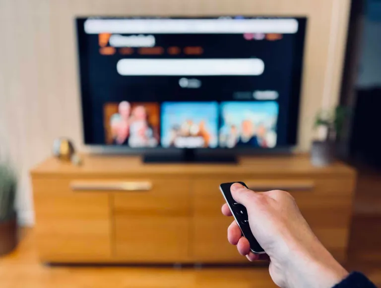 Forsidebilde til innlegget som viser en person med en fjernkontroll peke mot en TV hvor Filmotekets hjemmeside vises